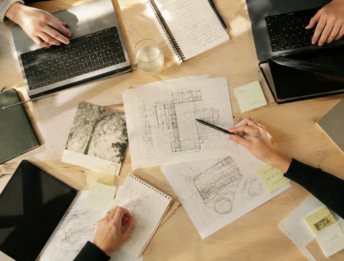 Collaborative planning session with laptops and architecture sketches on a table